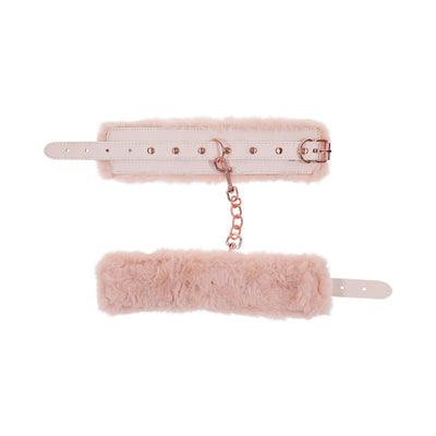 Light peach faux fur handcuffs with rose gold chain and adjustable buckle straps on white background.