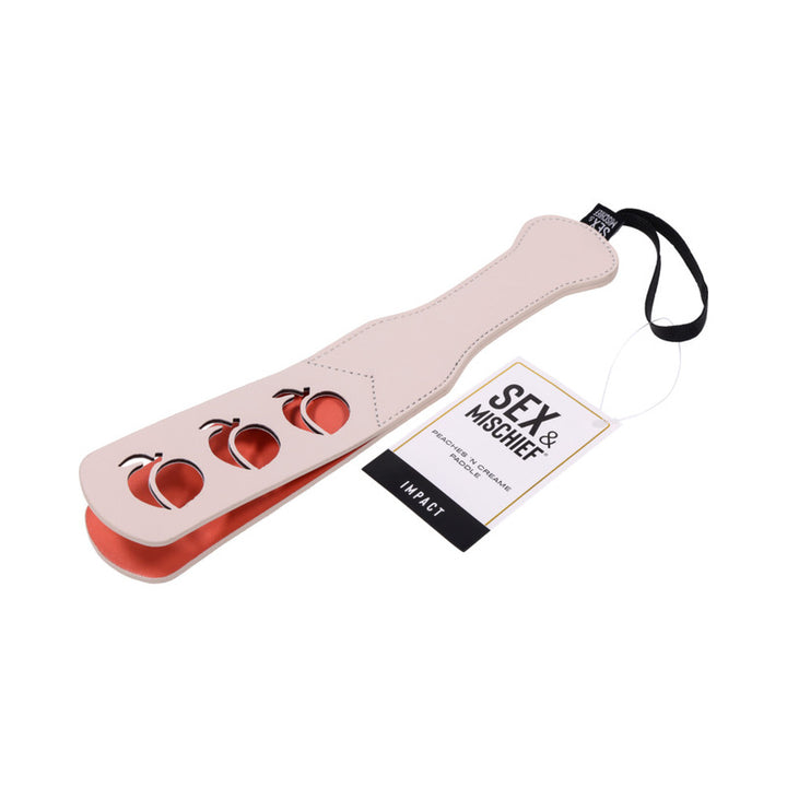 Light pink faux leather paddle with peach-shaped cutouts and black wrist strap, labeled Sex & Mischief Peaches n Creame Paddle.