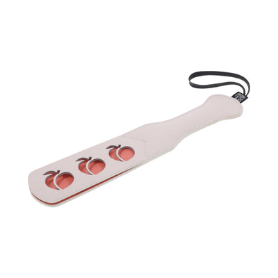 Light pink faux leather paddle with peach-shaped cutouts and black wrist strap on white background.