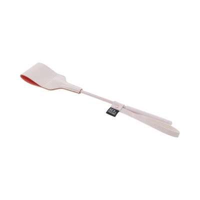 Peach-colored faux leather riding crop with a looped tip and wrist strap, 12 inches long for discreet use.