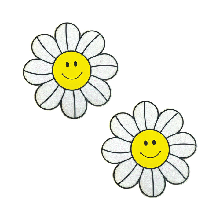 Pair of glittery white daisy nipple pasties with yellow smiley face centers and black petal outlines on white background.