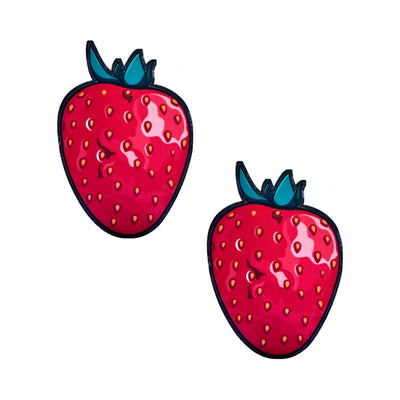 Pair of red strawberry-shaped edible nipple pasties with green leaves and yellow seed details on a white background.