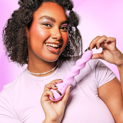 Smiling woman holding a pink VUSH Siren Twist Vibrator with a spiral design against a pink background.