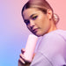 Woman in lavender hoodie holding a pink VUSH branded travel case against a pastel gradient background