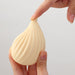 Close-up of a hand gently pressing the soft, ribbed tip of the ivory iroha+ KUSHI Renewal massager.
