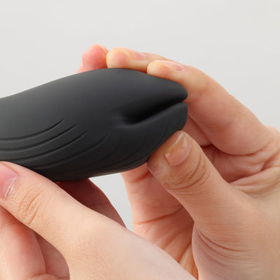 Close-up of hands holding the sleek black iroha+ YORU Renewal vibrator with soft, curved silicone design.
