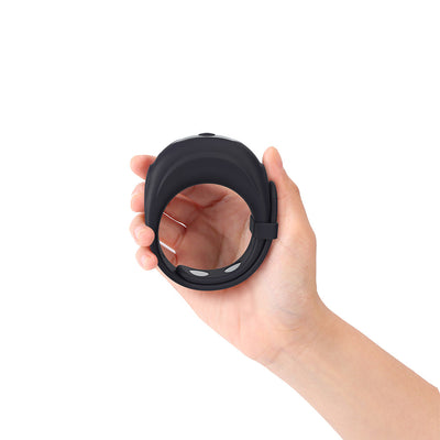 Hand holding a black adjustable silicone Dorcel Fit Vibe Ring with ergonomic design and control button on top.