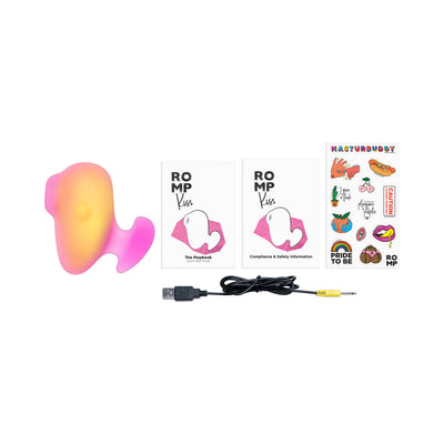 ROMP Kiss Pink/Coral clitoral suction toy with USB charging cable, user guides, and colorful sticker sheet on white background.