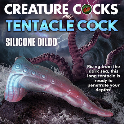 Iridescent red and blue silicone tentacle dildo with textured suckers and wide suction base on rocky shore background.