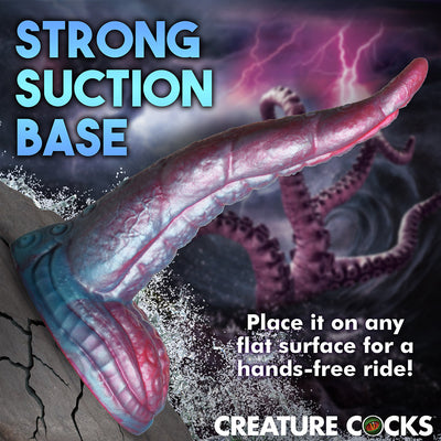 Iridescent red and blue tentacle dildo with textured suckers and strong suction base on cracked rock surface.