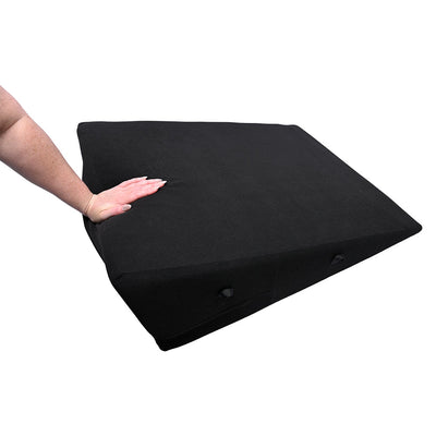 Black wedge-shaped sportsheets pivot positioner plus with a hand pressing down to show its soft foam texture.