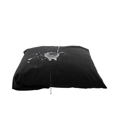 Black waterproof pillow protector with water splashing on top, demonstrating liquid resistance.