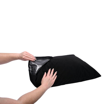 Hands holding a black Sportsheets Pivot Pillow Protector showing its waterproof inner lining and hook and loop closure.