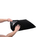 Hands holding a black Sportsheets Pivot Pillow Protector showing its waterproof inner lining and hook and loop closure.
