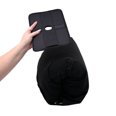 Hand holding black Sportsheets Pivot Pillow Protector above a black cylindrical pillow on white background