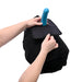 Hands demonstrating the Sportsheets Pivot Pillow Protector with a blue silicone attachment on a black pillow.