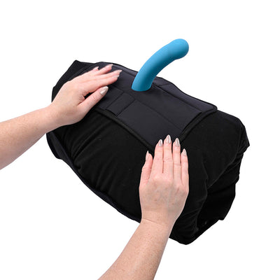 Hands adjusting a black Sportsheets Pivot Pillow Protector with a blue silicone attachment on a rolled pillow.