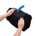 Hands adjusting a black Sportsheets Pivot Pillow Protector with a blue silicone attachment on a rolled pillow.
