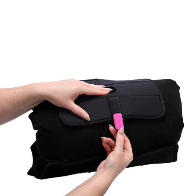 Hands demonstrating the black Sportsheets Pivot Pillow Protector with a pink accessory inserted through its secure flap closure.