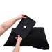 Hands holding the black Sportsheets Pivot Pillow Protector above a matching black pillow on a white background.