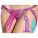 Adjustable purple strap-on harness worn on hips with three colorful silicone dildos in pink, purple, and blue.