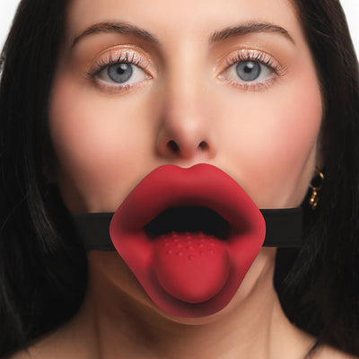 Close-up of a woman wearing a red vibrating lips mouth gag with textured tongue and black adjustable strap.