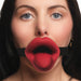Close-up of a woman wearing a red vibrating lips mouth gag with textured tongue and black adjustable strap.