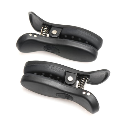 Pair of black vibrating nipple clamps with silicone padding and metal springs shown on white background.