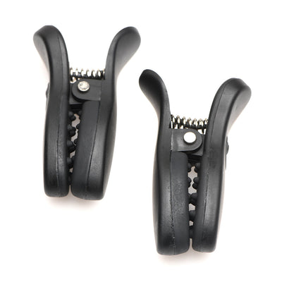 Pair of black vibrating nipple clamps with textured silicone grips and metal springs isolated on white background.