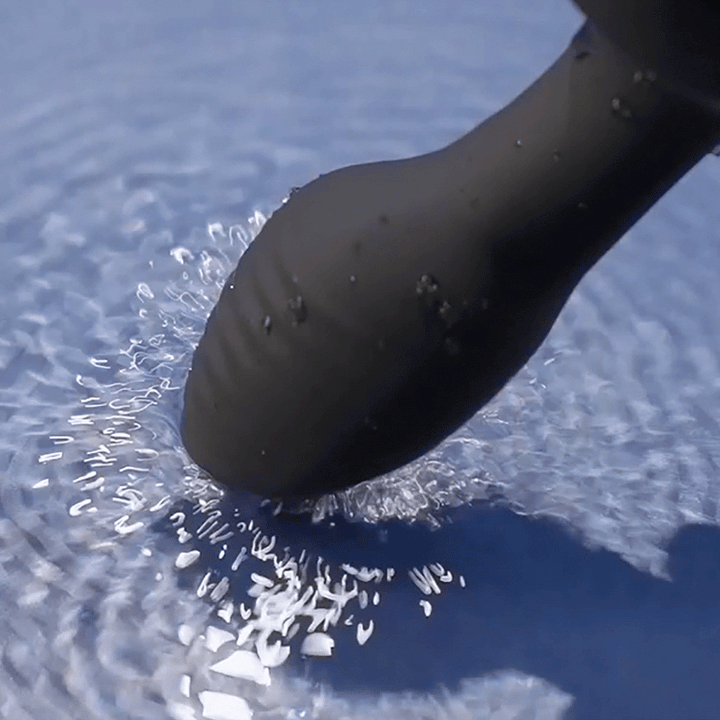 Black ergonomic rotating butt plug with water droplets, shown in water to highlight waterproof feature.