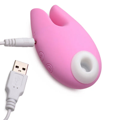 Pink silicone clitoral stimulator with bunny ears and USB charging cable on white background.