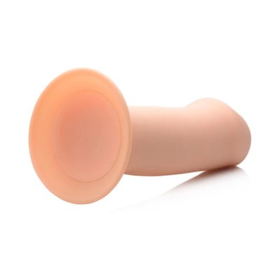 Beige squeezable thick phallic dildo with suction cup base lying on a white surface.