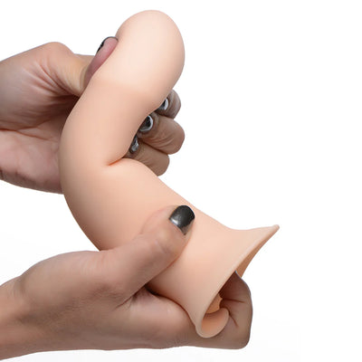Hands bending a beige, thick, squeezable silicone dildo with a suction cup base against a white background.