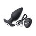 Black silicone vibrating butt plug with wireless remote and USB charging cable on white background.