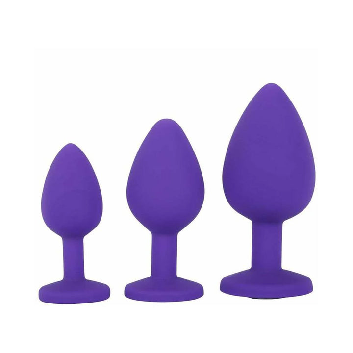 Three purple silicone butt plugs in small, medium, and large sizes with tapered tips and flared bases.