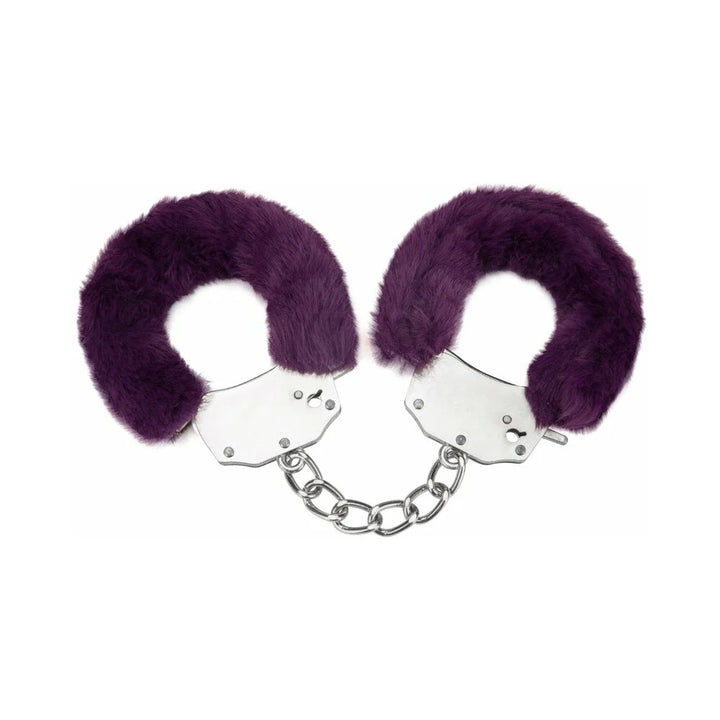 Pair of metal handcuffs wrapped in soft purple furry covers connected by a short chain on white background.