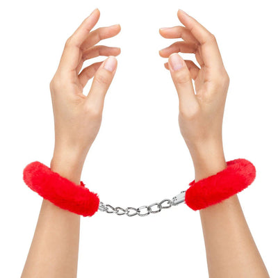 Hands wearing red furry handcuffs connected by a metal chain against a white background.