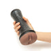 Hand holding a black Myu Ultrastroker V1 stroker with a caramel-colored realistic textured opening.