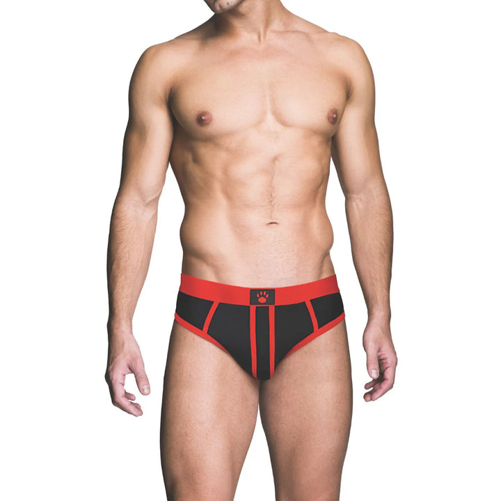 Male model wearing black and red Prowler ass-less brief with red waistband and trim on white background.