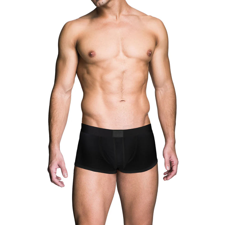 Male model wearing black Prowler Red Ass-Less Trunk underwear, front view on white background.