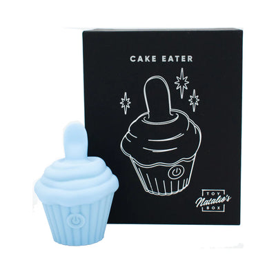 Light blue silicone cupcake-shaped flicker stimulator with power button, shown next to black packaging box with white cupcake illustration.