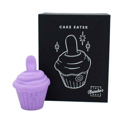 Purple silicone cupcake-shaped flicker stimulator with power button, displayed next to black Cake Eater packaging box.