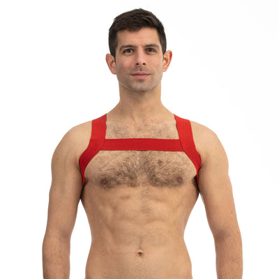 Man wearing a red Prowler sports harness with wide straps across chest and shoulders against a white background.