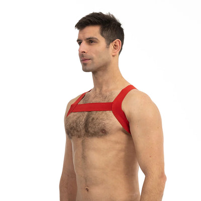 Man wearing a red Prowler sports harness with wide straps across chest and shoulders against white background.