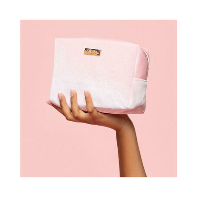 Hand holding a soft pink velvet VUSH storage case with gold logo plaque against a matching pink background.