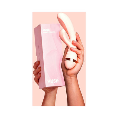 Hand holding a pale pink VUSH Muse Rabbit Vibrator and its matching pink packaging box against a soft pink background.