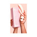 Hand holding a pale pink VUSH Muse Rabbit Vibrator and its matching pink packaging box against a soft pink background.
