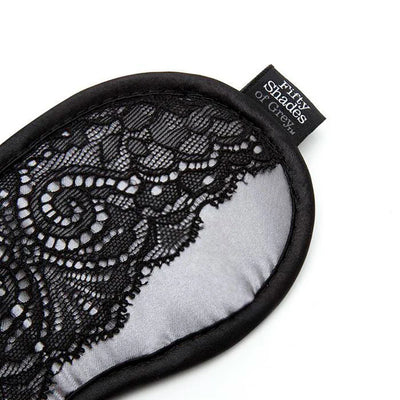 Silver satin blindfold with intricate black lace overlay and Fifty Shades of Grey branded tag on white background.