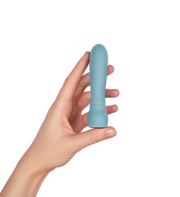 Hand holding a compact, smooth blue silicone personal massager with a rounded tip and ergonomic shape.