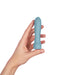 Hand holding a compact, smooth blue silicone personal massager with a rounded tip and ergonomic shape.